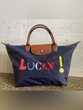 Longchamp navy tote with multicolor 'LUCKY' lettering and brown leather trim